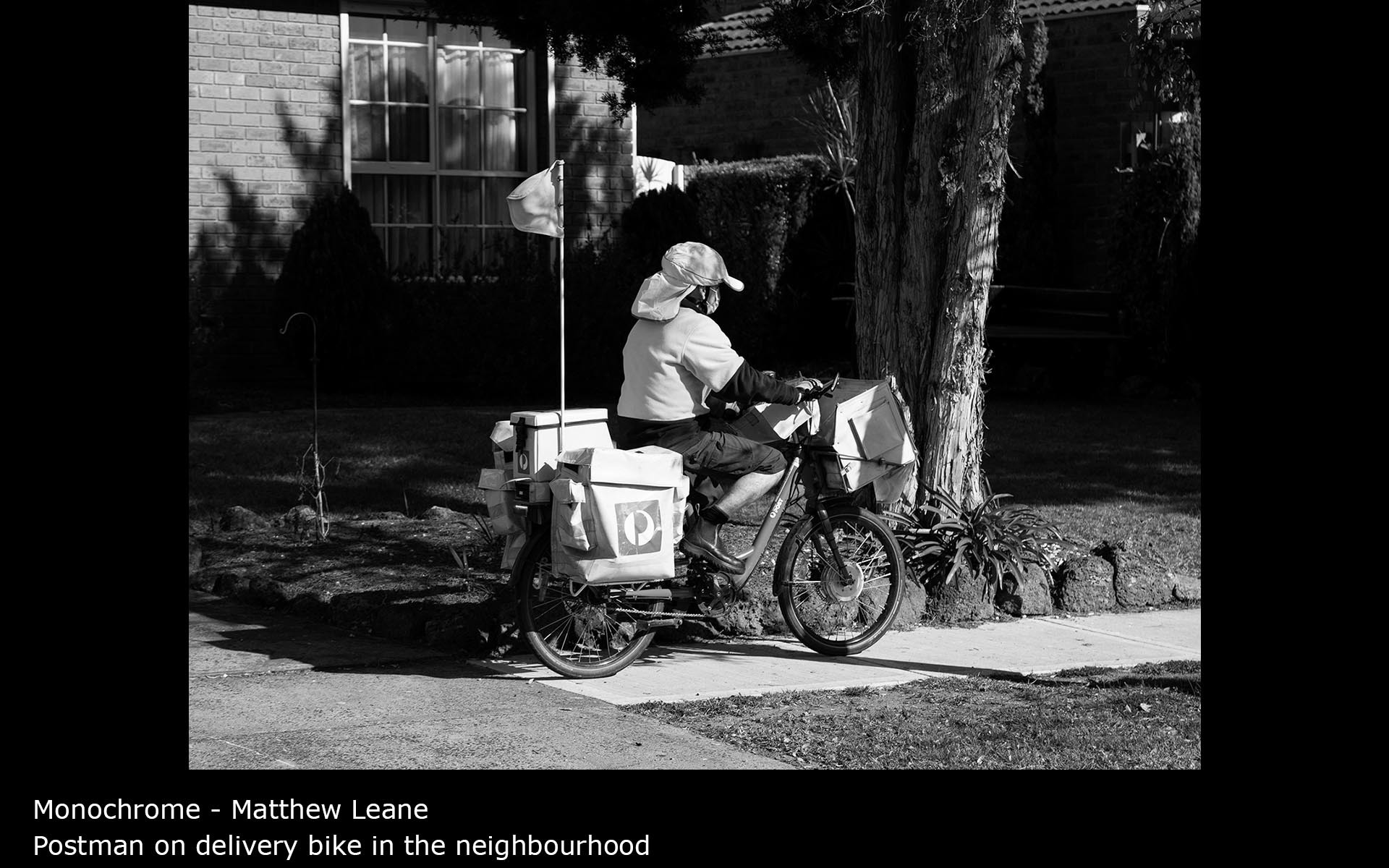 Postman on delivery bike in the neighbourhood - Matthew Leane